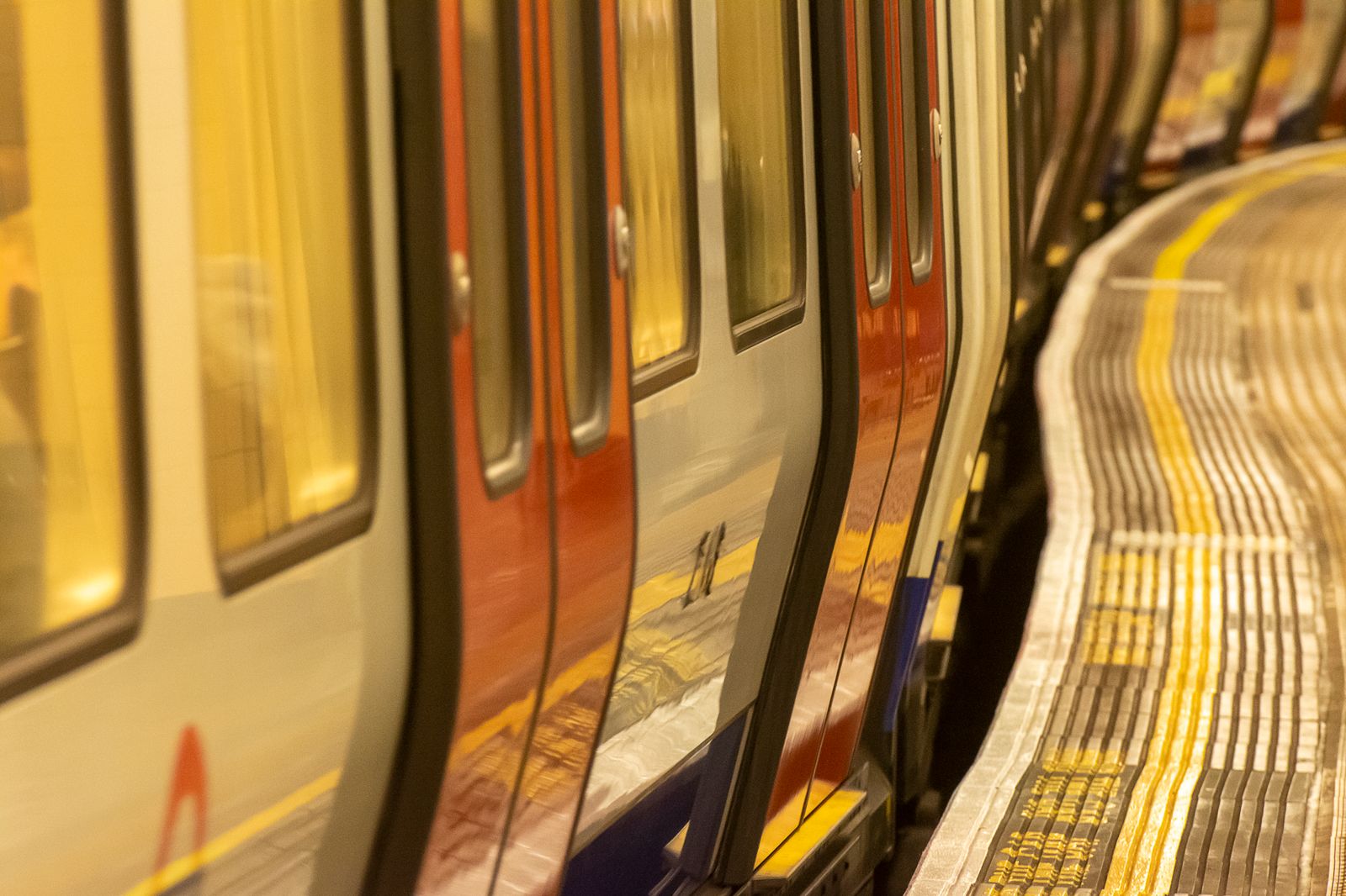 A curved London Underground platform as a train arrives